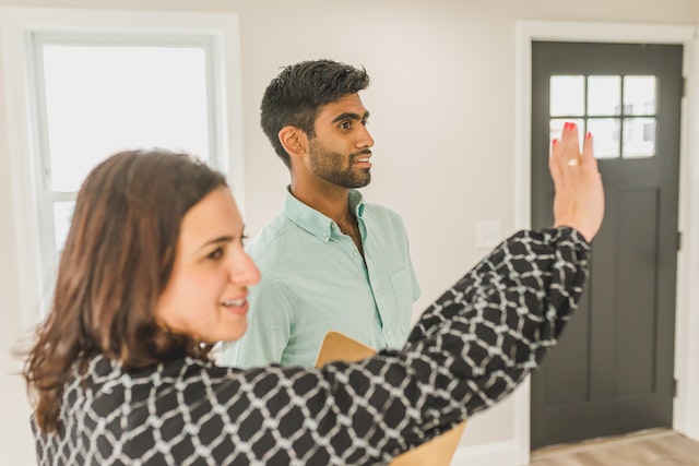 property owner in white and black shirt giving a tour to a prospective tenant in a blue shirt